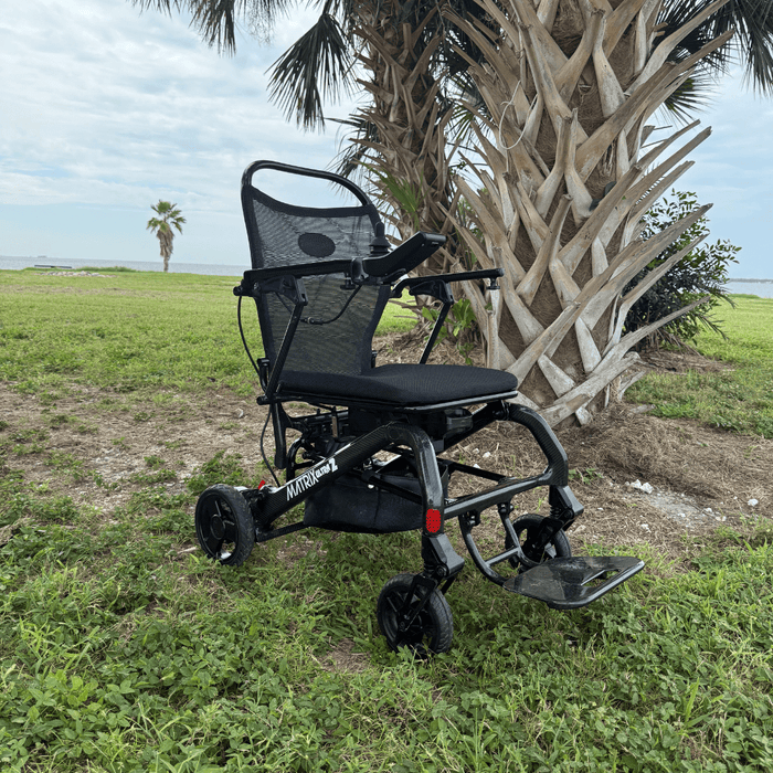 Matrix Ultra 2 Power Wheelchair on grass with palm trees and ocean in the background
