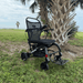 Matrix Ultra 2 Power Wheelchair on grass with palm trees and ocean in the background