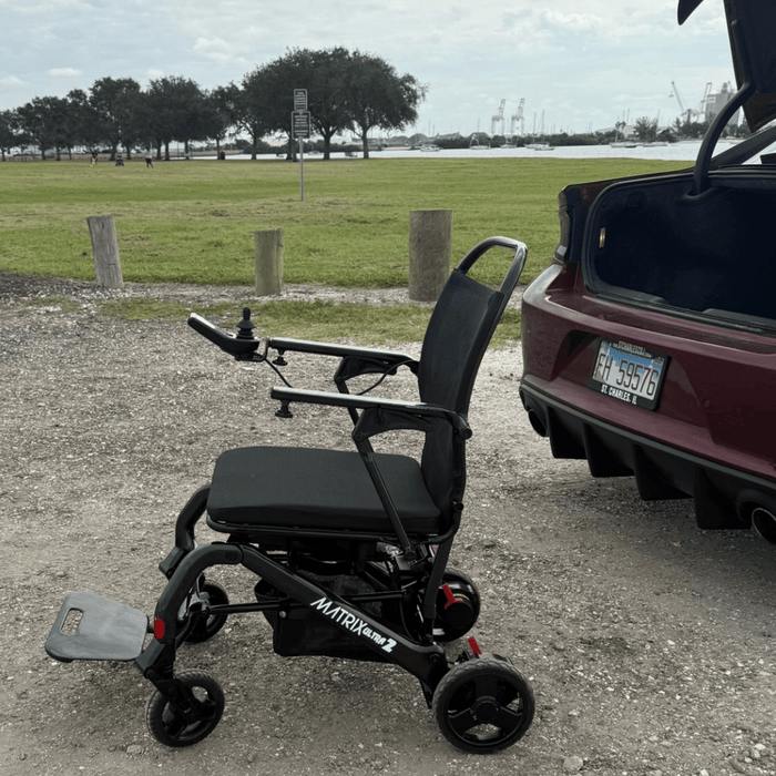 Matrox Ultra 2 Wheelchair next to a vehicle with a license plate in an outdoor setting.