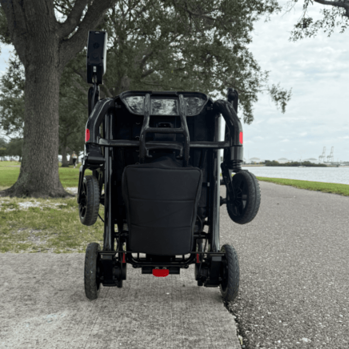 Matrix Ultra 2  wheelchair  folded on a paved path with trees and water in the background