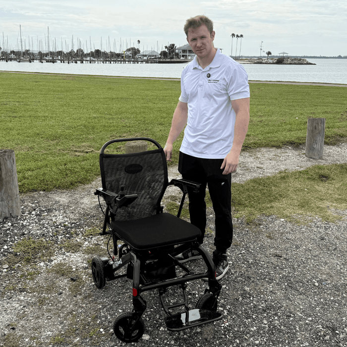 Man standing next to a folding chair outdoors by a waterfront