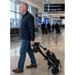 Man wheeling the folded MobiFree mobility scooter like a trolley through an airport terminal