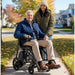 Man enjoying outdoor mobility on Journey Air Elite Max power chair with woman walking behind