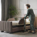 Woman adjusting a starsleep side tabl in a room with plants and a large window.