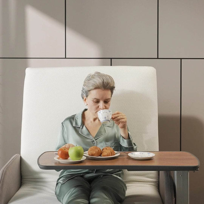 Woman sitting on Starsleep motion table with a small table in front of her, drinking from a cup.