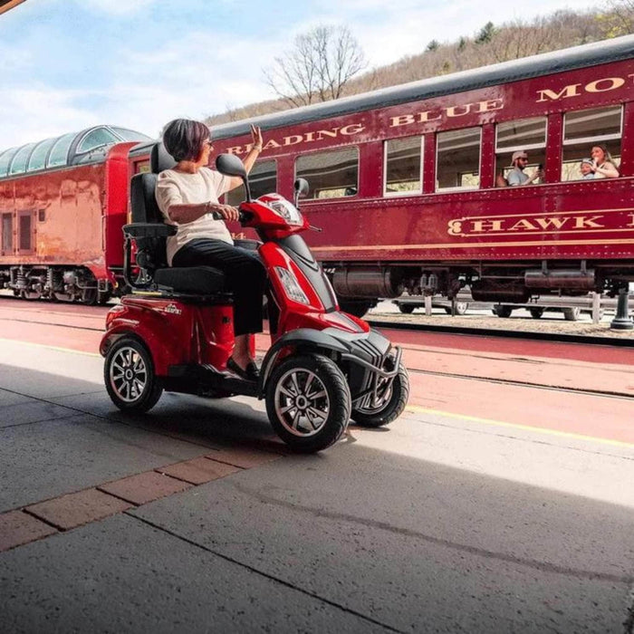 Woman Sitting in Baja Raptor 2 Scooter Color Red Side View and Waving people at the train