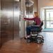 Go Chair Pride Mobility Color White- Woman Using for Elevator 